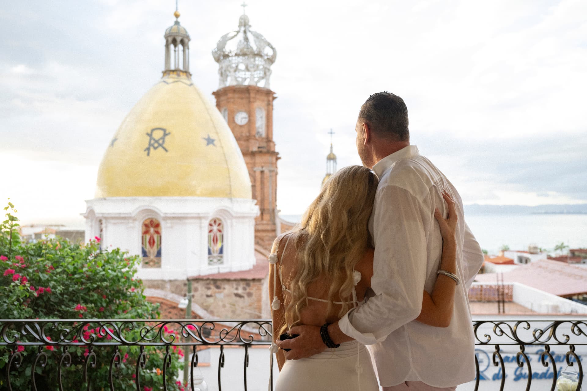 Couple embracing on a balcony terrace facing the Puerto Vallarta cathedral dome after the proposal