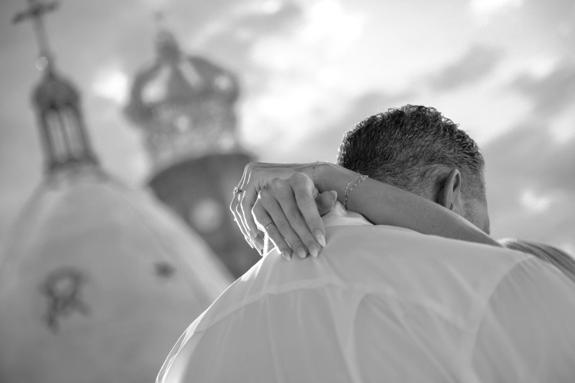 Black and white close up of the engagement ring on her hand resting on his shoulder, the cathedral blurred behind