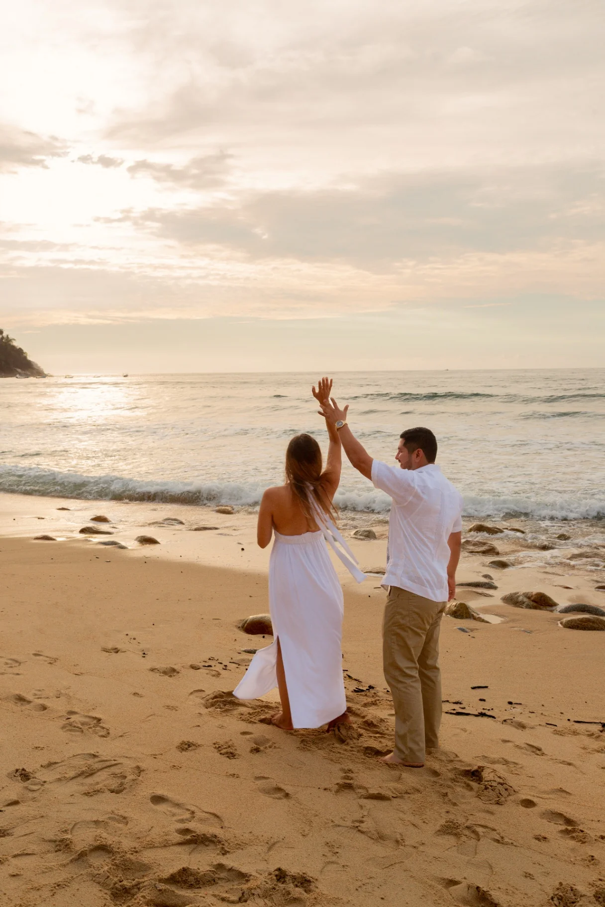 Couple celebrating their engagement on a Pacific beach at sunset